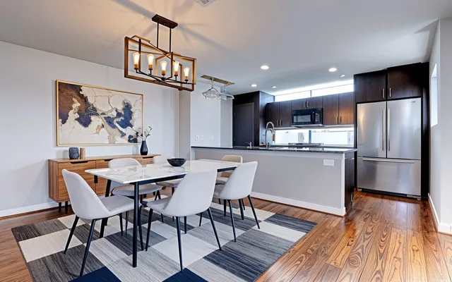 a kitchen with stainless steel appliances granite countertop a dining table chairs refrigerator and sink