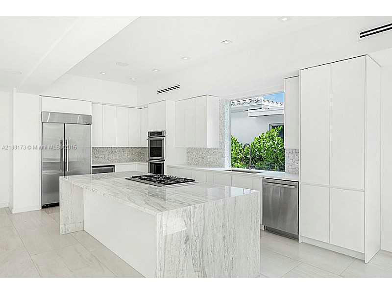 1760 Cleveland Road Miami Beach, FL 33141 - Photo 3 of 14 a kitchen with kitchen island a stove a refrigerator a sink and white cabinets with wooden floor