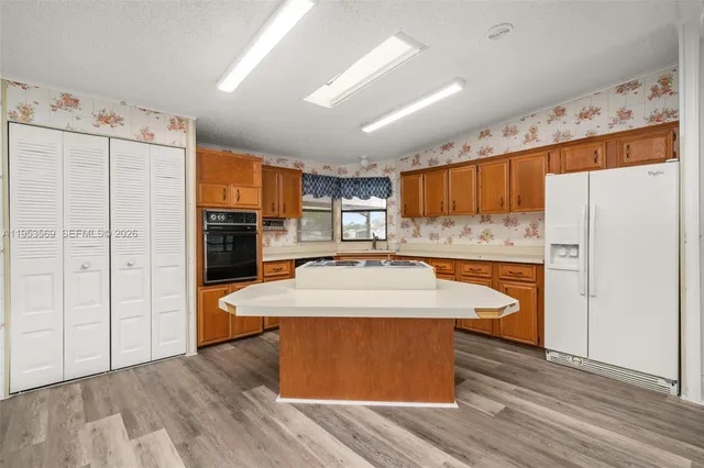 a large kitchen with kitchen island a stove a refrigerator a sink and dishwasher with wooden floor