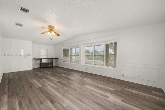 a view of an empty room with a window and wooden floor