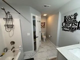 a bathroom with a granite countertop sink a toilet and shower