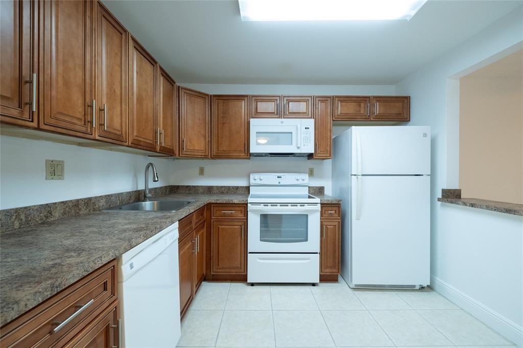 9233 Southwest 8th Street, Unit 222 Boca Raton, FL 33428 - Photo 2 of 29 a kitchen with a refrigerator sink and cabinets