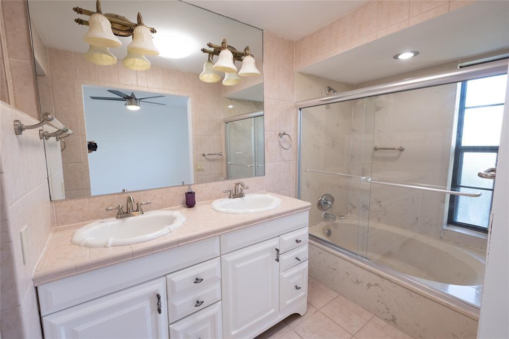 9233 Southwest 8th Street, Unit 222 Boca Raton, FL 33428 - Photo 26 of 29 a bathroom with a granite countertop sink a mirror a shower and a bathtub