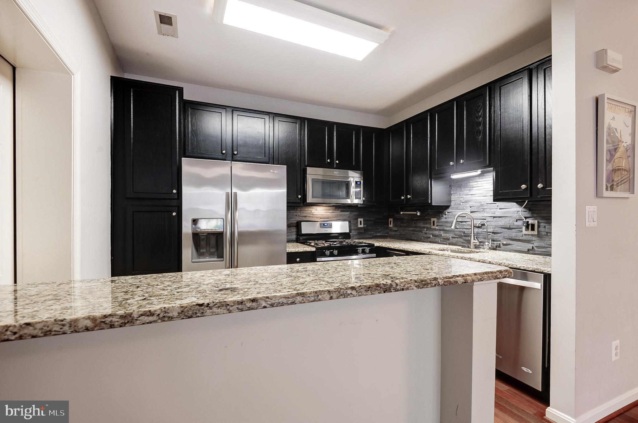 11407 Gate Hill Place, Unit 112 Reston, VA 20194 - Photo 12 of 28 a kitchen with stainless steel appliances granite countertop a sink a stove a refrigerator a washer and dryer