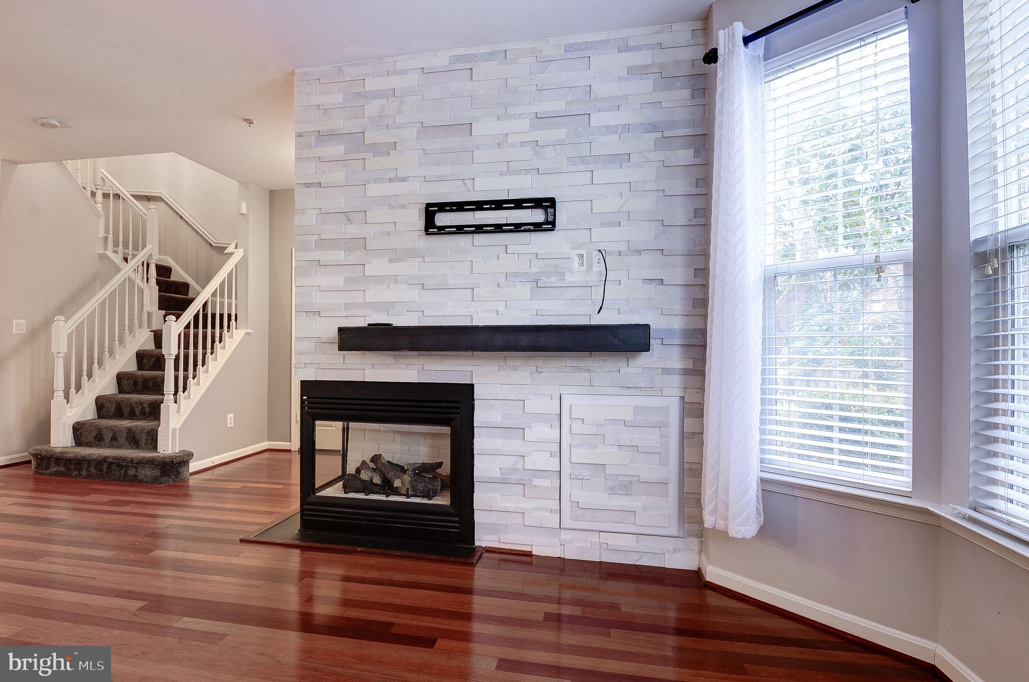 11407 Gate Hill Place, Unit 112 Reston, VA 20194 - Photo 7 of 28 a hallway with a wooden floor a fireplace and a window