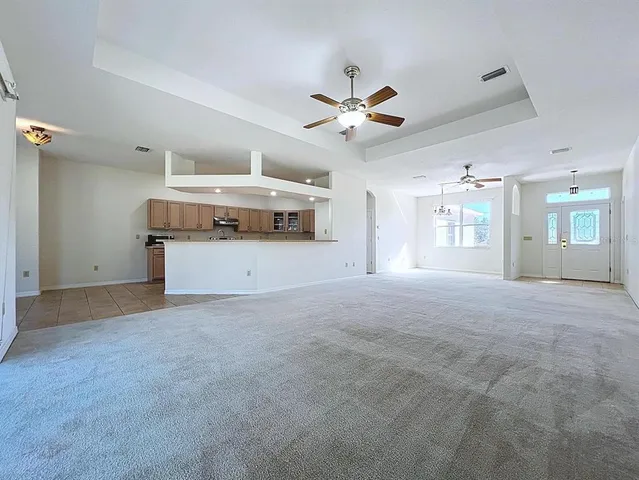 an empty room with chandelier fan and windows