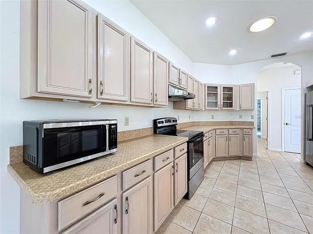 a large kitchen with stainless steel appliances granite countertop a stove top oven a sink dishwasher and a refrigerator