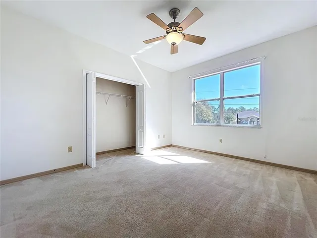 an empty room with a ceiling fan and window