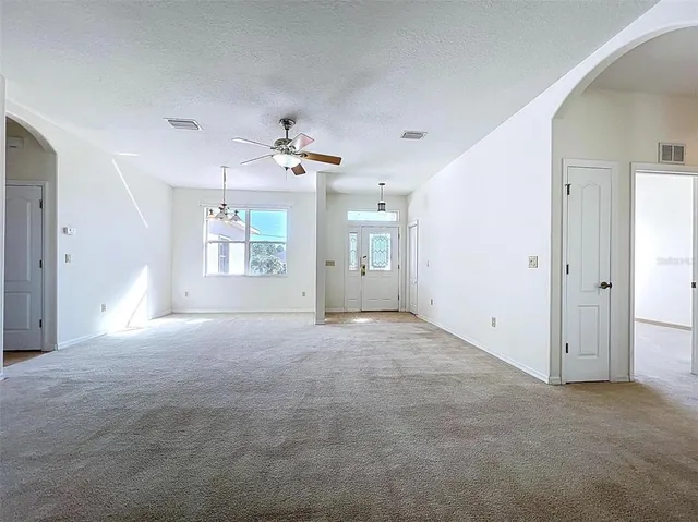an empty room with windows and ceiling fan