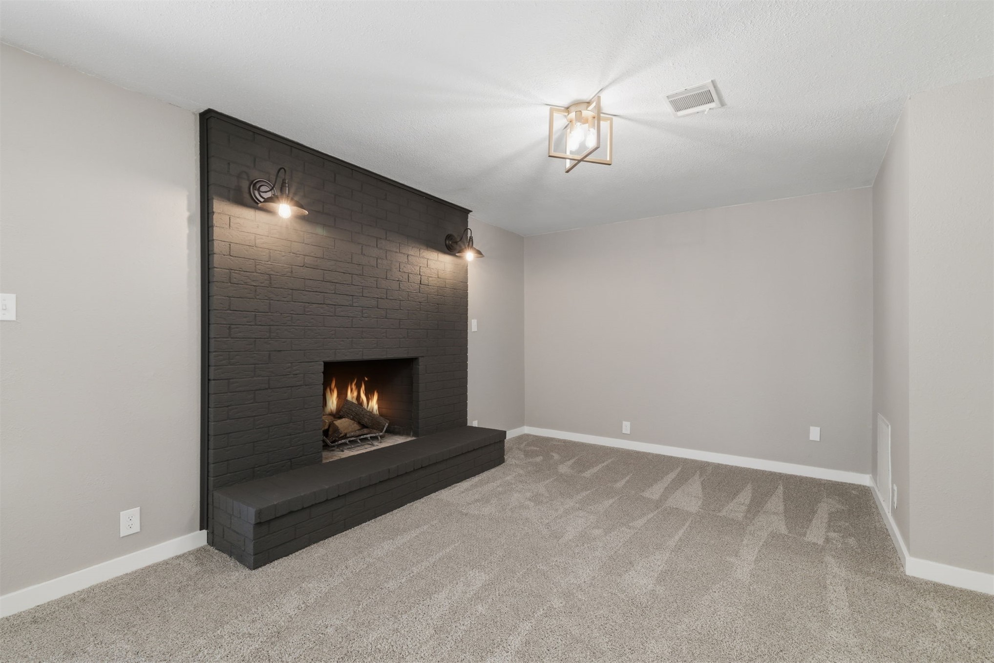 633 Swinney Road Mead, OK 73449 - Photo 8 of 32 Expansive room featuring a brick fireplace with a hearth, wall-mounted sconces, and overhead lighting