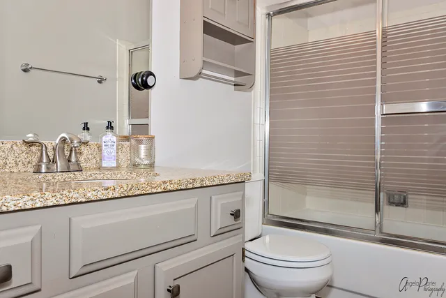 a bathroom with a granite countertop sink toilet and shower
