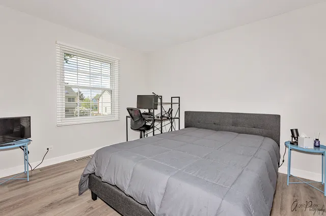 a large bed sitting in a bedroom next to a window with chair