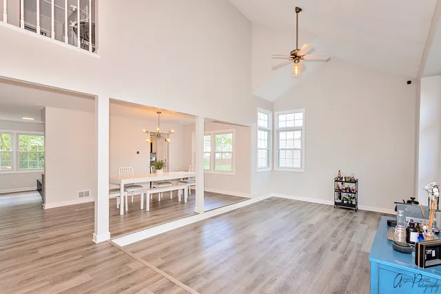 a dining room with wooden floor a chandelier a glass table and windows