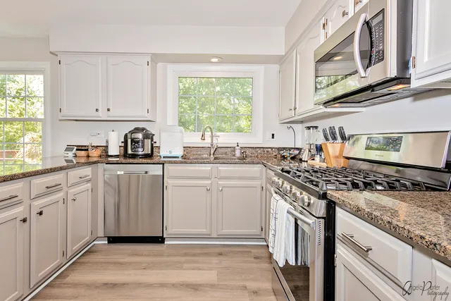 a kitchen with white cabinets appliances and a window