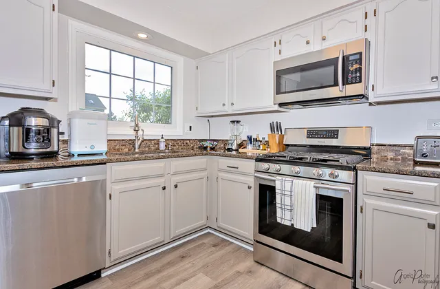 a kitchen with cabinets stainless steel appliances and window
