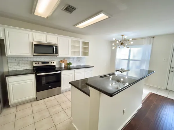 a kitchen with stainless steel appliances granite countertop a stove top oven a sink a counter space and cabinets