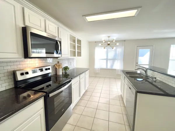 a kitchen with stainless steel appliances granite countertop a stove a sink and a microwave