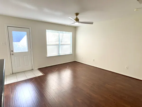 an empty room with wooden floor chandelier and windows