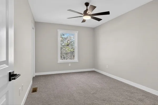 an empty room with a window and a fan