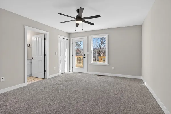 an empty room with ceiling fan and windows
