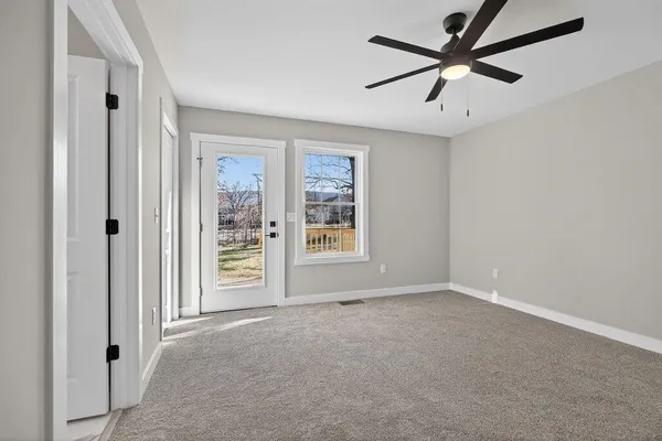 an empty room with windows and fan
