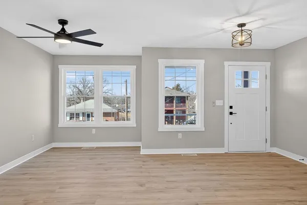 a view of an empty room with a window and wooden floor