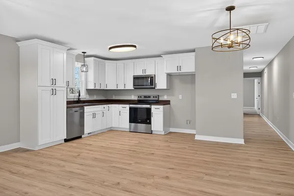 a large kitchen with cabinets wooden floor and stainless steel appliances