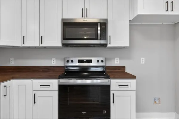 a kitchen with stainless steel appliances granite countertop white cabinets and a stove top oven