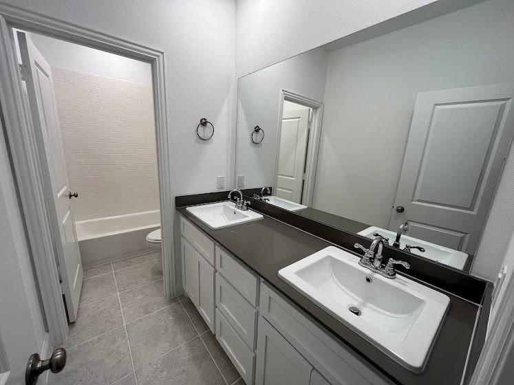 1408 Rendyn Street Anna, TX 75409 - Photo 15 of 23 Double vanity with integrated sinks, dark countertop, and chrome fixtures