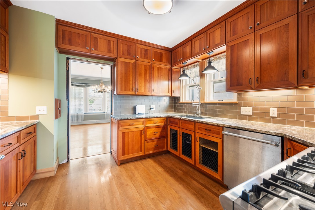 24510 Lake Road Bay Village, OH 44140 - Photo 21 of 45 Kitchen with backsplash, light wood-style flooring, dishwasher, cooktop, and brown cabinets