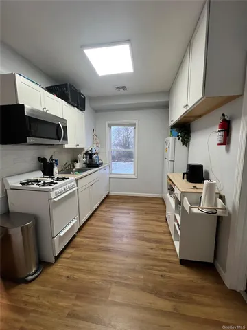 a kitchen with stainless steel appliances a stove top oven a sink a window and cabinets