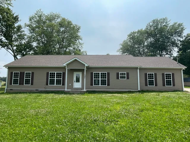 a front view of house with yard and trees all around