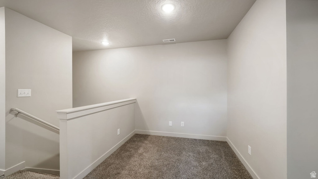 1223 East 1775 North Payson, UT 84651 - Photo 36 of 45 Carpeted loft area featuring a low wall with white trim, a visible stairway with handrail, recessed lighting, and neutral wall paint