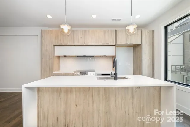 a large kitchen with kitchen island a sink stainless steel appliances and a chandelier