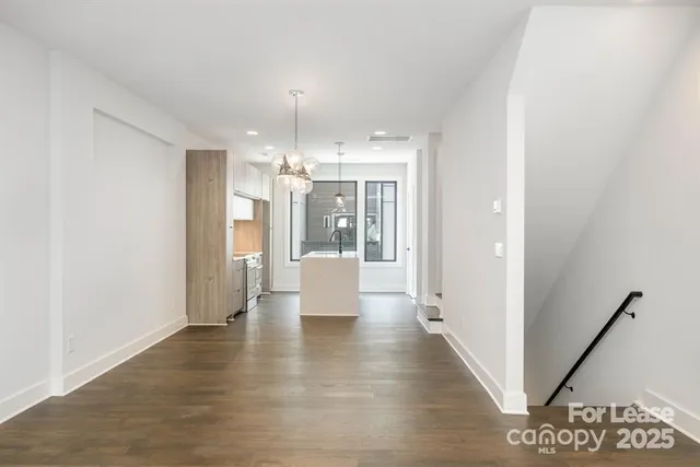 a view of a hallway with wooden floor and chandelier