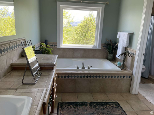 7030 West 2100 North Mendon, UT 84325 - Photo 38 of 67 Built-in soaking tub with deck-mounted faucet, surrounded by tiled surfaces with decorative diamond accents