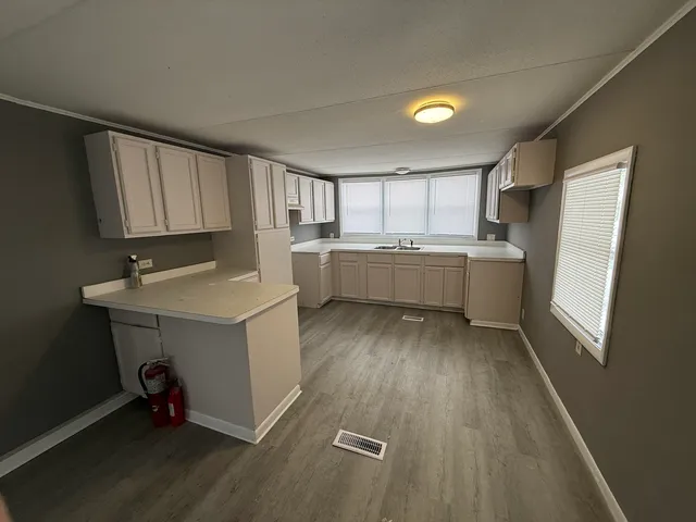 a room with a sink wooden floor and cabinets