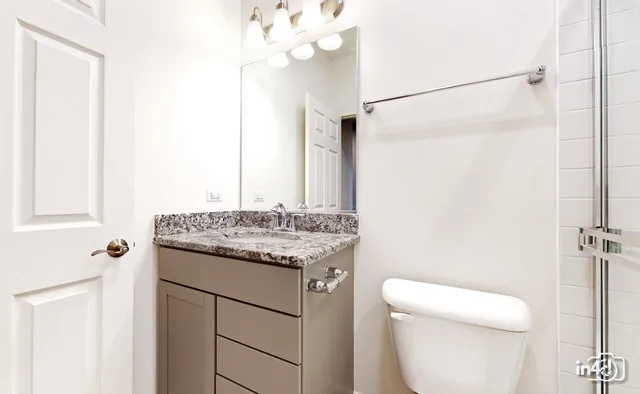 a bathroom with a granite countertop sink a toilet and mirror