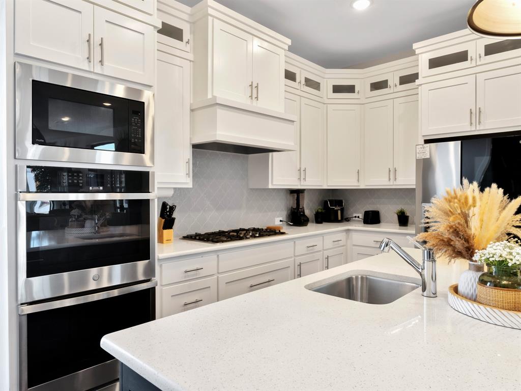 602 Winners Circle Rowlett, TX 75088 - Photo 10 of 28 Kitchen with light stone countertops, appliances with stainless steel finishes, glass insert cabinets, and recessed lighting