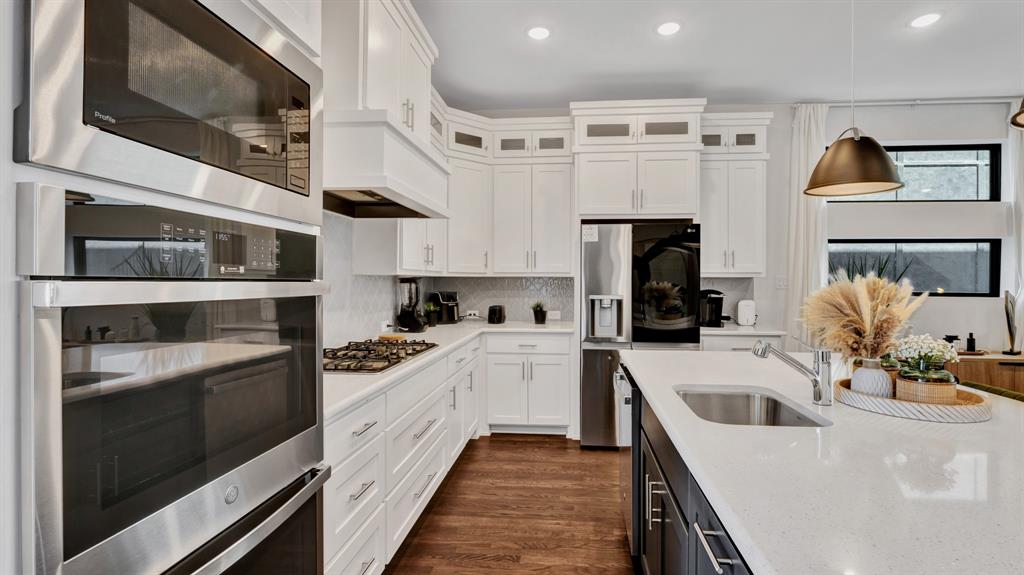 602 Winners Circle Rowlett, TX 75088 - Photo 7 of 28 Kitchen featuring hanging light fixtures, appliances with stainless steel finishes, white cabinetry, light stone counters, and dark wood-style floors
