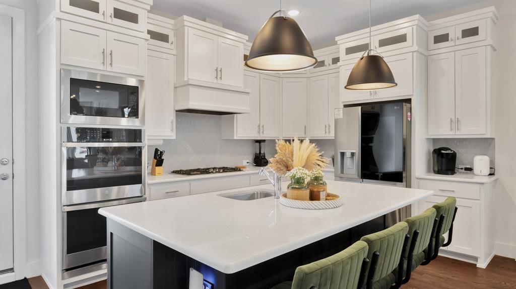 602 Winners Circle Rowlett, TX 75088 - Photo 8 of 28 Kitchen with tasteful backsplash, stainless steel appliances, a kitchen island with sink, white cabinetry, and light stone countertops