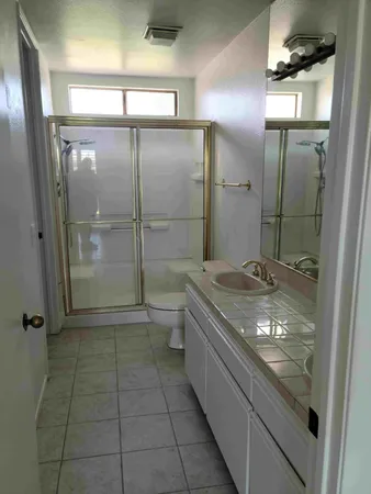 a bathroom with a granite countertop sink a toilet and shower