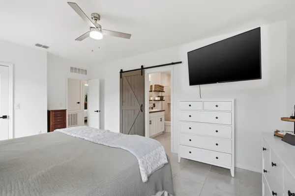 a bedroom with a large bed and a flat tv screen on dresser