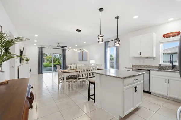 a large kitchen with kitchen island a counter top space a sink stainless steel appliances and cabinets