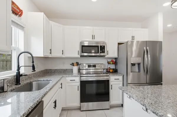 a kitchen with stainless steel appliances granite countertop a sink a stove and refrigerator