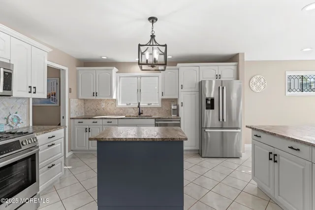 a large kitchen with stainless steel appliances kitchen island granite countertop a refrigerator and a stove top oven