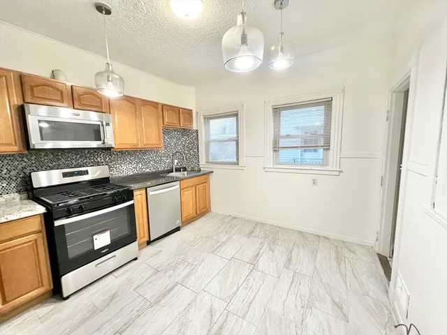 a kitchen with stainless steel appliances granite countertop a stove a sink and a microwave