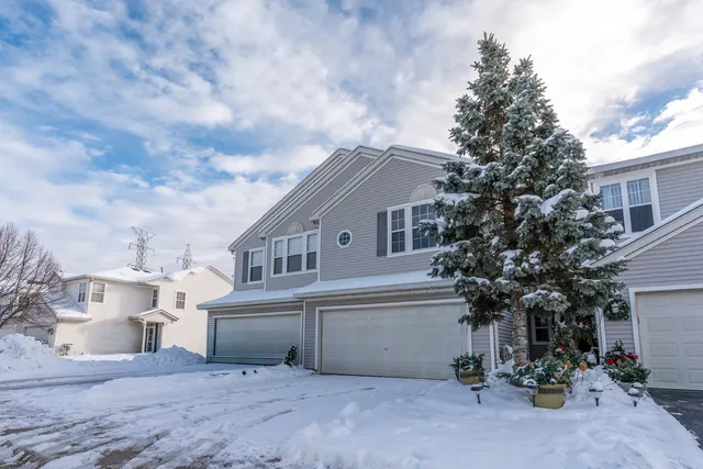 a view of a white house next to a yard with plants and trees