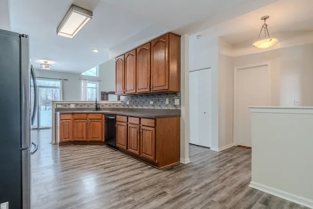 a kitchen with stainless steel appliances granite countertop a stove a sink dishwasher and a refrigerator with wooden floor