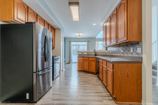 a kitchen with stainless steel appliances granite countertop a refrigerator a stove and a sink